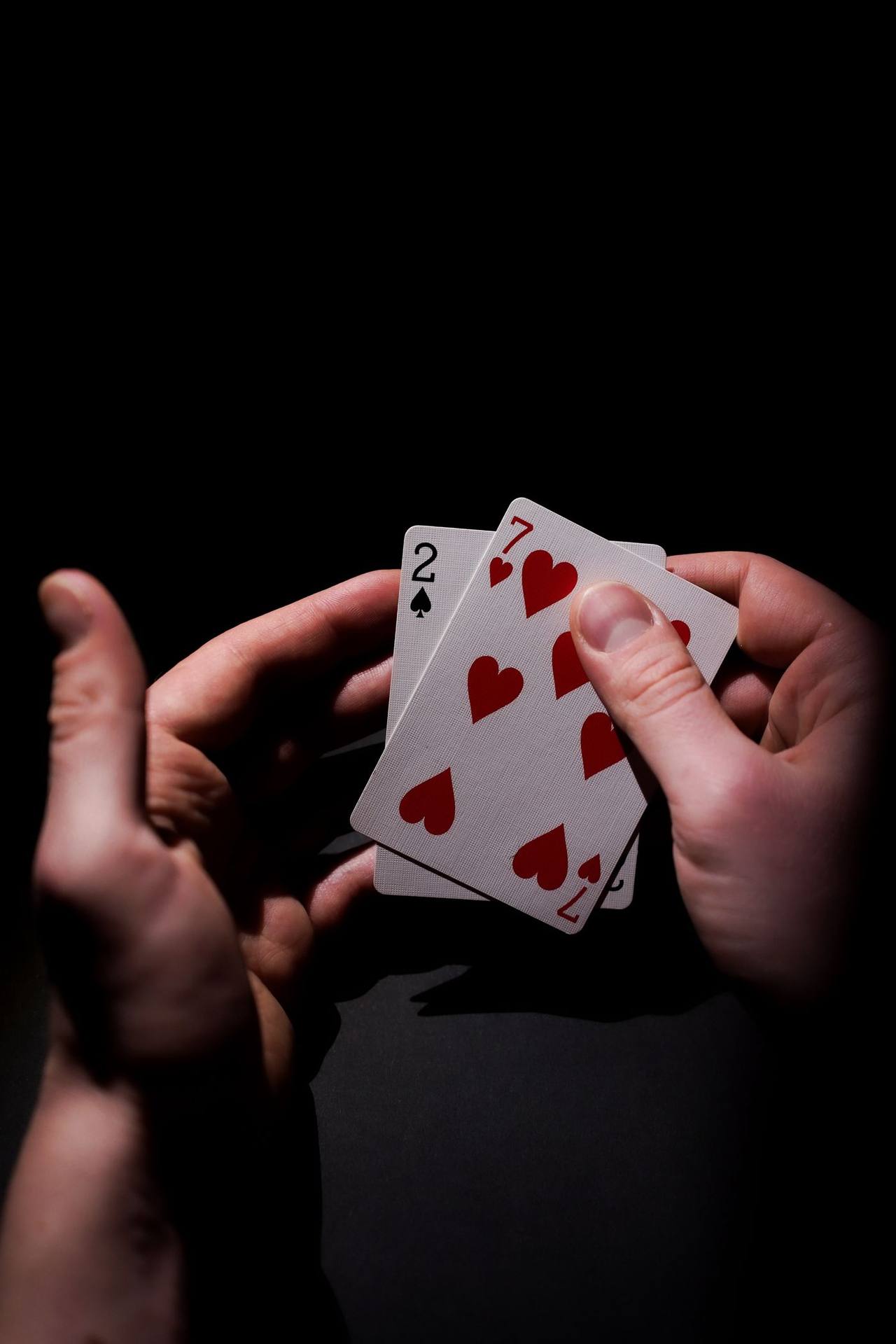 Tangan pemain memegang dua kartu poker tertutup